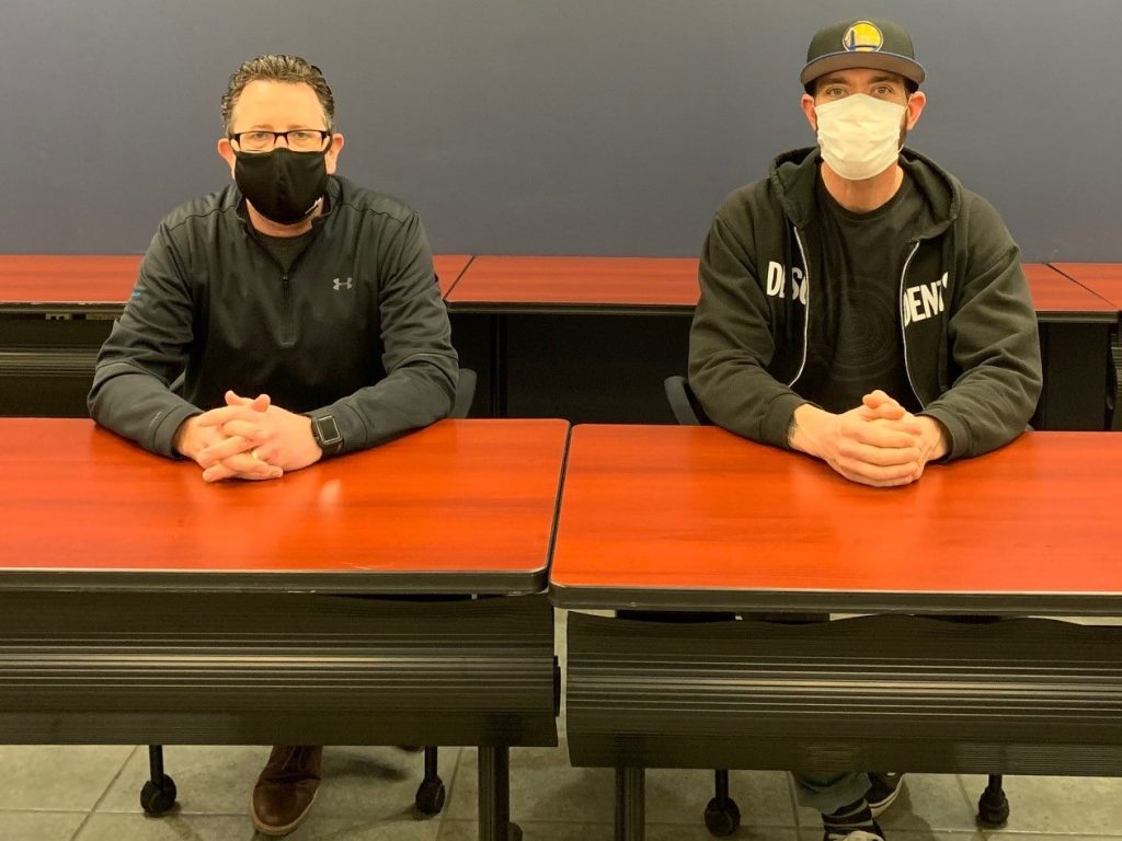 Two Plasman employees sitting at desk wearing masks