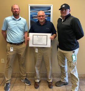 Three Plasman employees holding award from GM for Certificate of Excellence for Plasman Fort Payne Manufacturing