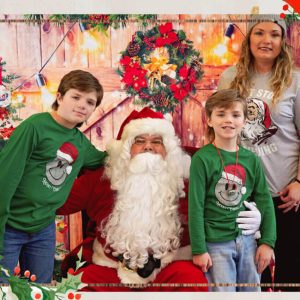 Two children and their mother, a Plasman employee, posing with Santa Claus who is sitting in a red chair