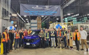Large group of Plasman employees standing around blue Honda 23CR-V at Plasman Windsor 3 Manufacturing