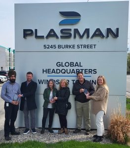 Plasman and Can-Am employees holding Can-Am awards in front of Global Headquarters sign outside in Windsor, Ontario