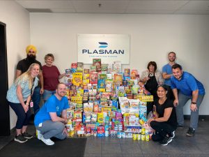 Plasman Windsor 3 Manufacturing employees standing around large pile of cereal and food for donation