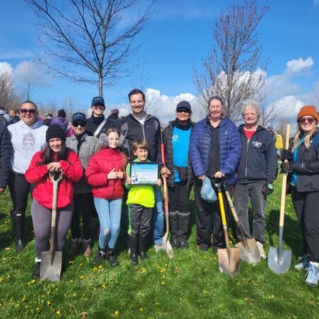 Group of adults and children from Plasman holding shovels at annual tree planting for ERCA