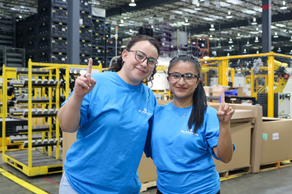 Two people pose holding up #1 finger at Plasman Fort Payne Manufacturing