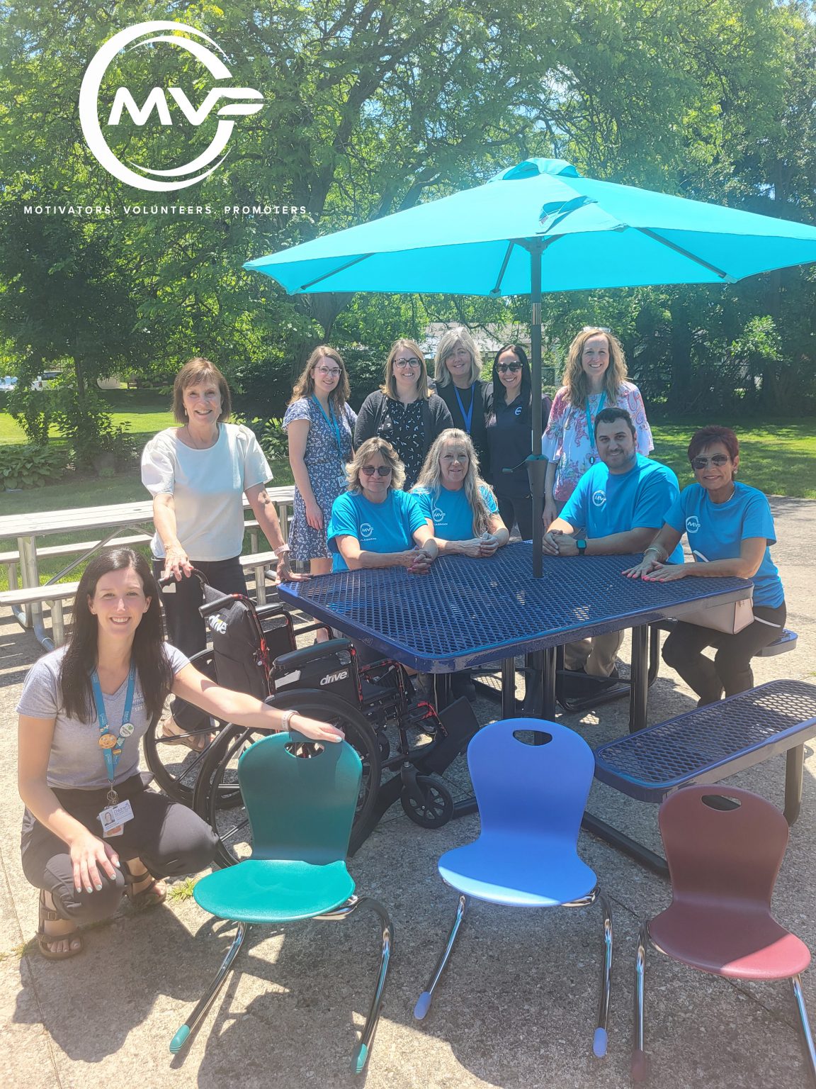 Group of volunteers and therapists sitting at an accessible picnic table with zuma rocker chairs