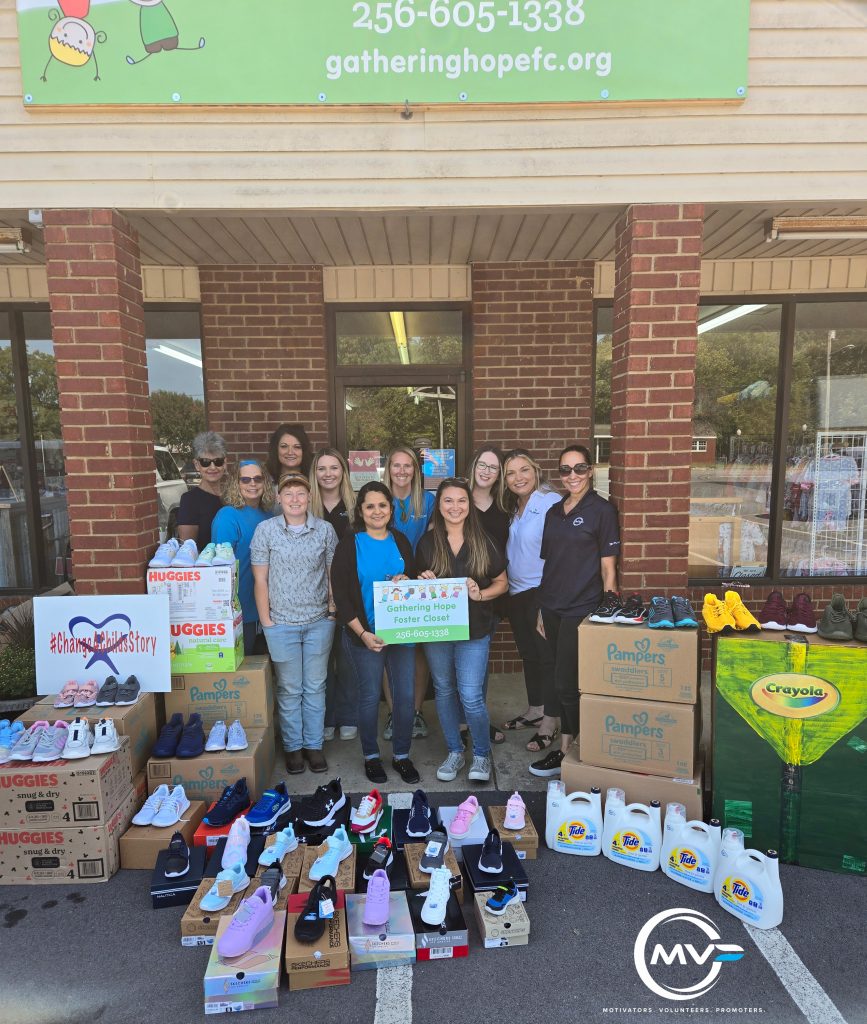 Group of people standing in front of store front of Gathering Hope Foster Closet with donations around them