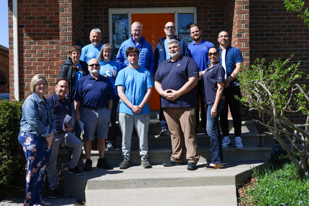 Group of Plasman MVP ambassadors along with WRYM respresentatives standing on a porch in front of the WRYM residence