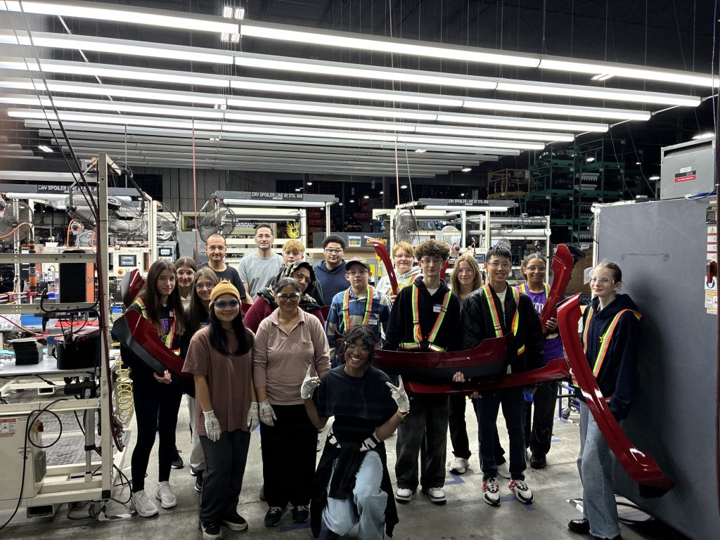 Group of Students on plant floor holding car parts