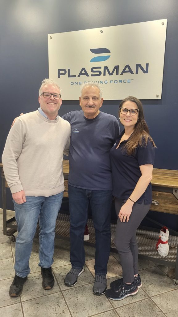 Richard Brooke, Moe, and Colette Labadie standing together in front of Tecusmeh Manufacturing's Plasman sign in the lobby