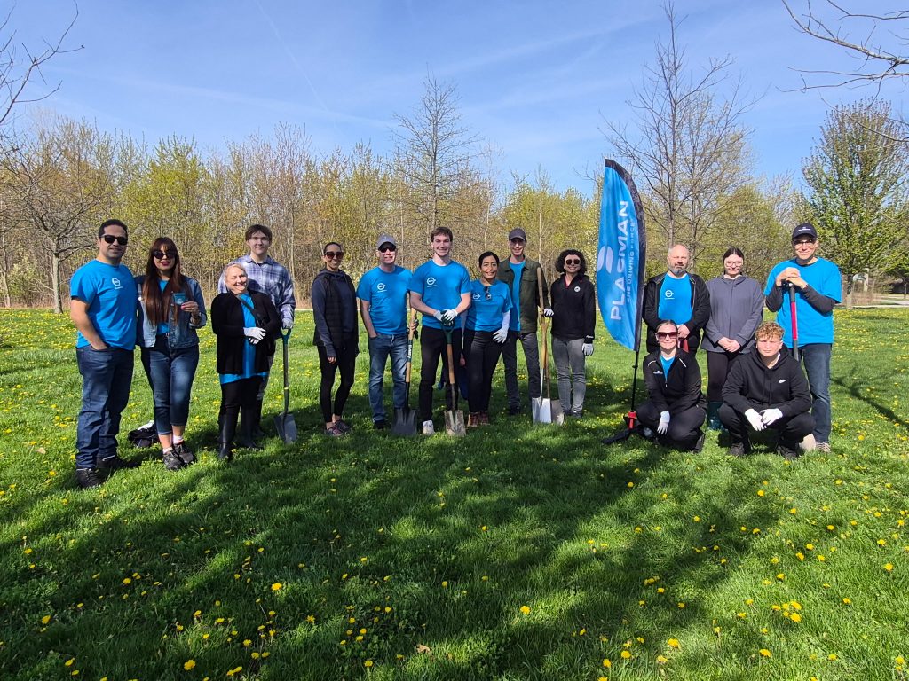 Group of Plasman MVP ambassadors standing together next to a Plasman flag in a field where they will plant trees