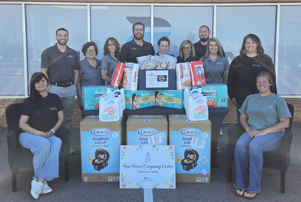 Plasman MVP ambassadors and Pregnancy representatives around a table of donations including diapers, child car seats, detergent and clothes